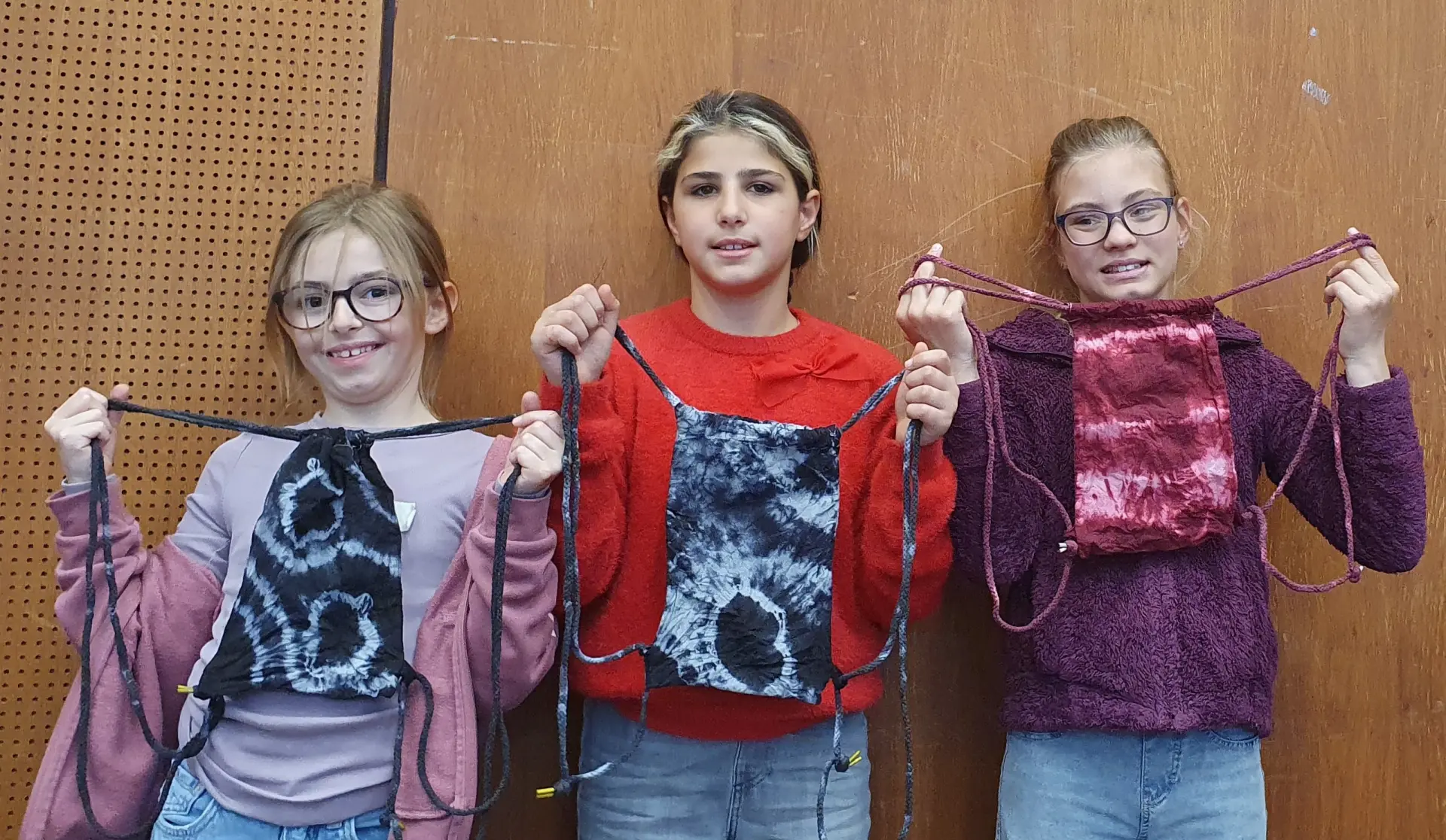 Schülerinnen halten selbst gestaltete Batikbeutel