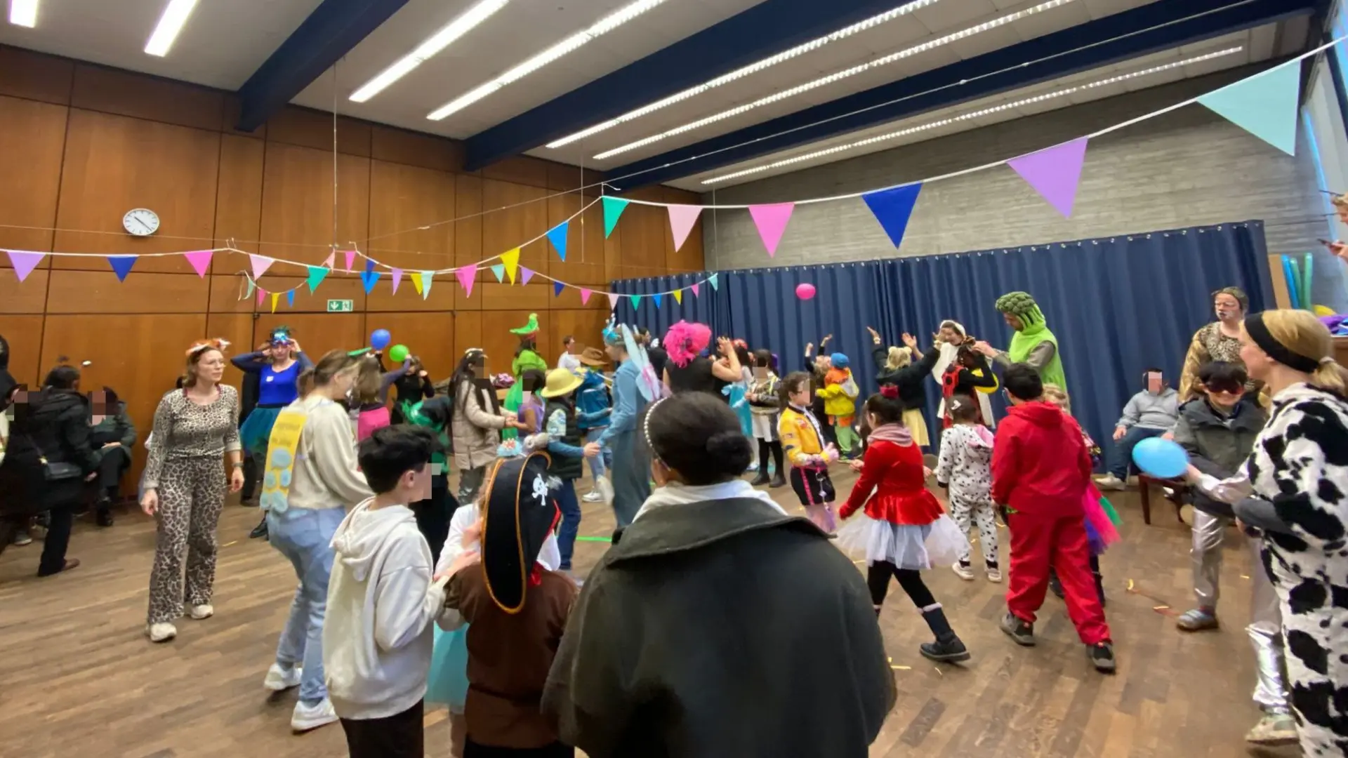 Die Schüler*innen feiern Karneval in der Aula in bunten Kostümen