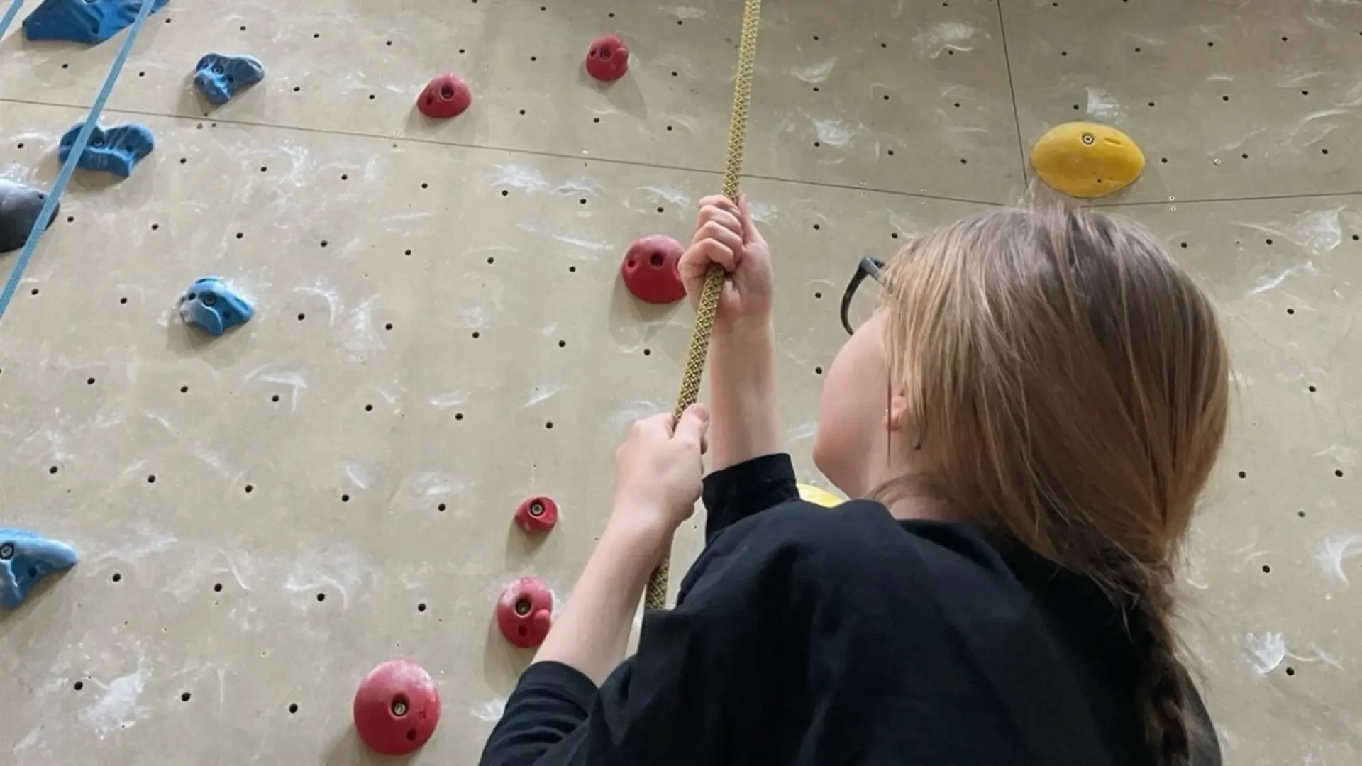 Schülerin klettert an Kletterwand 