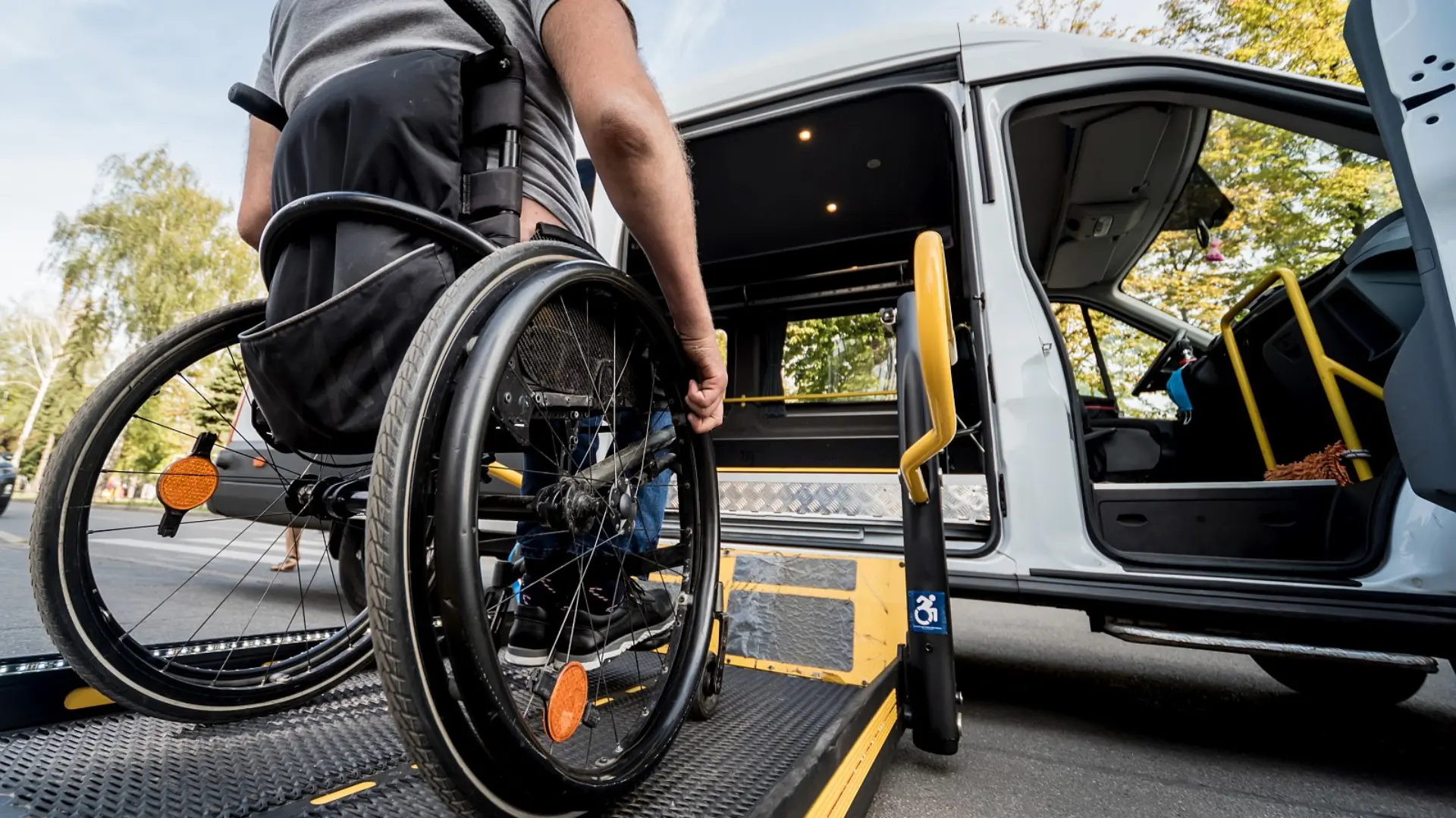 Rollstuhlfahrer fährt über eine Rampe in einen für Rollstühle ausgebauten Wagen rein.