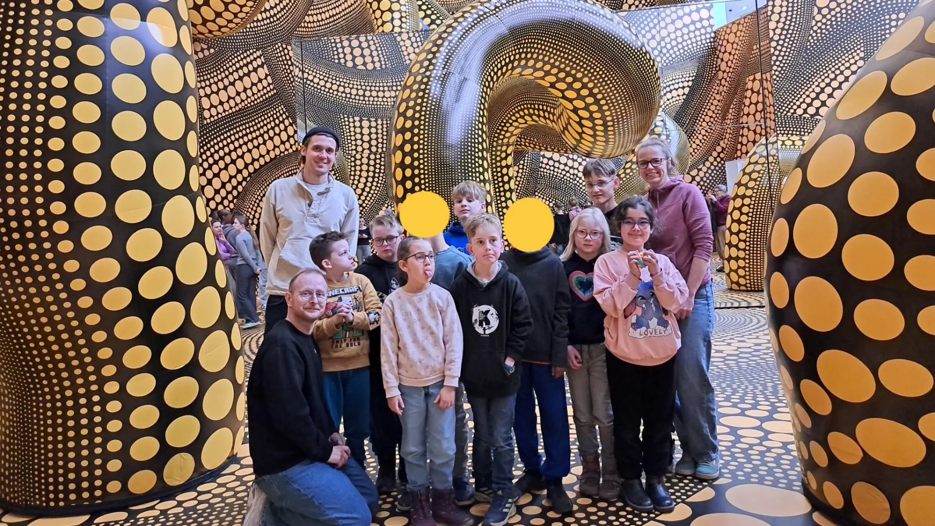 Das Foto zeigt die Kinder der Delfin-Klasse und die Lehrkräfte inmitten eines Kunstwerks von Kusama.