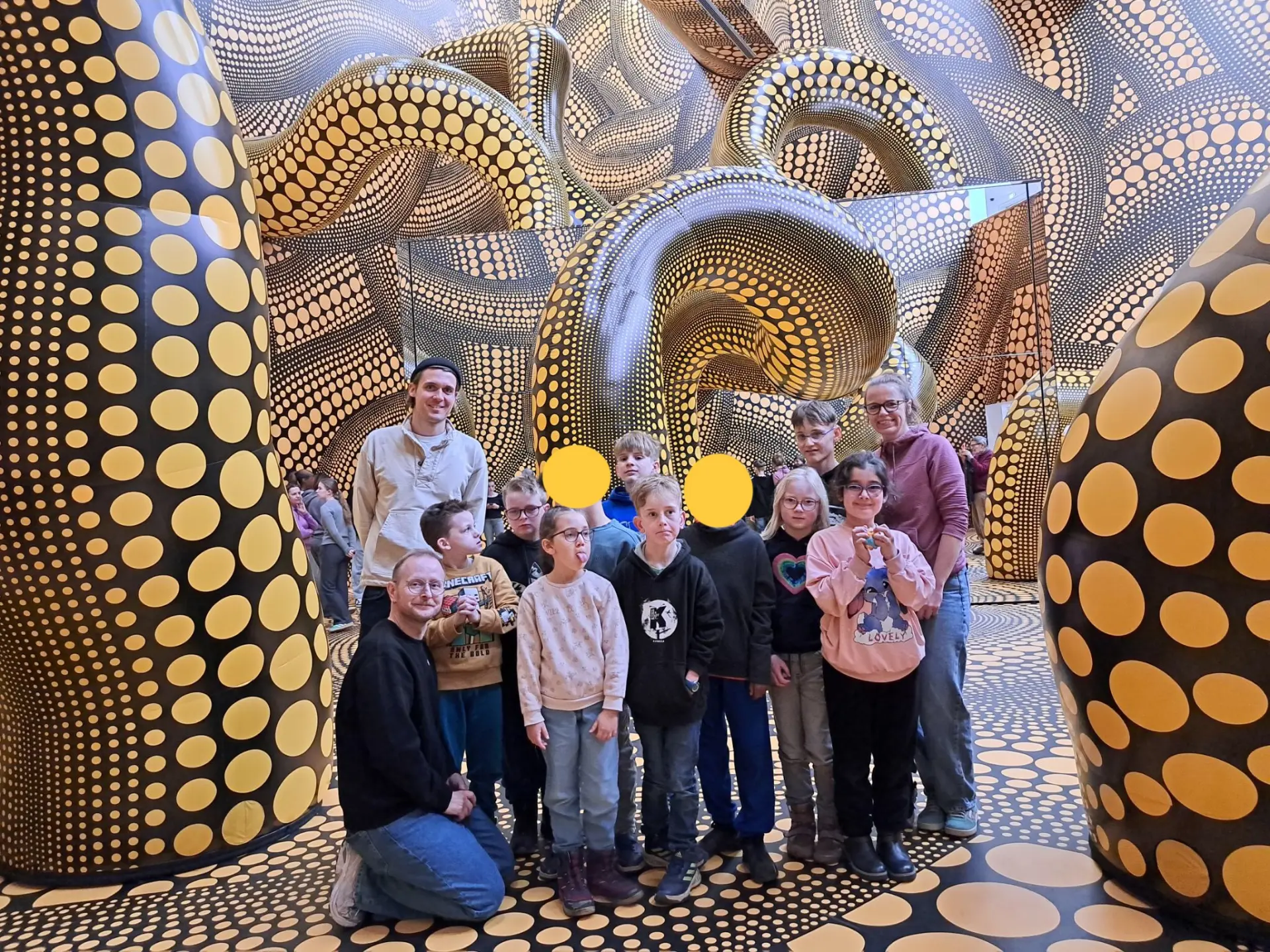 Das Foto zeigt die Kinder der Delfin-Klasse und die Lehrkräfte inmitten eines Kunstwerks von Kusama.