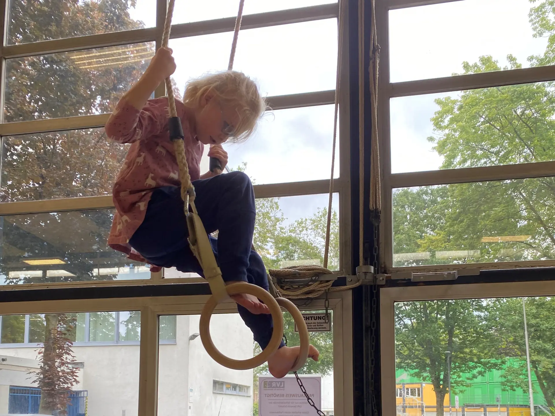 Schüler turnt an Ringen in der Turnhalle